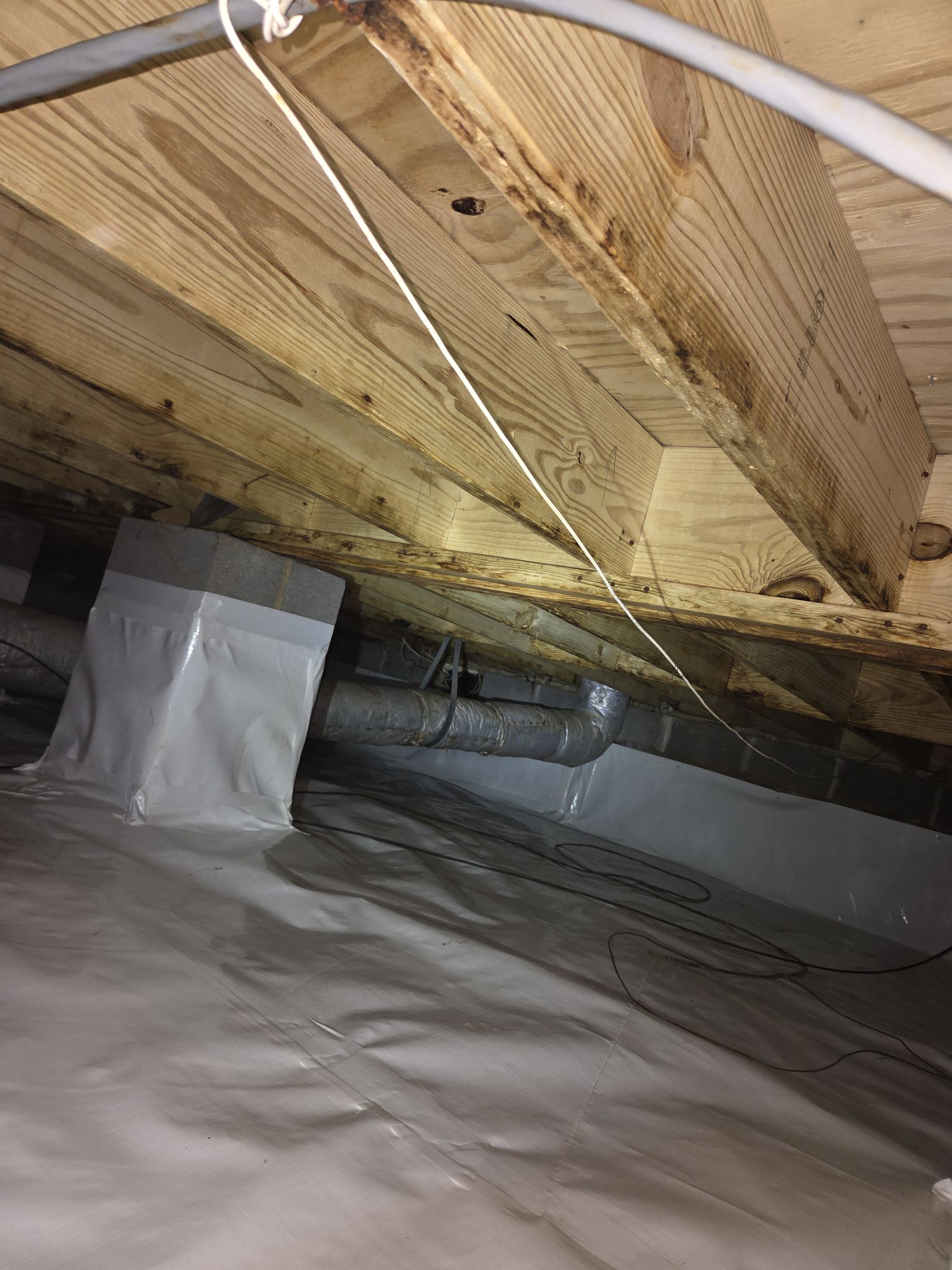 Close-up of a support pier wrapped in white vapor barrier inside a finished crawlspace encapsulation
