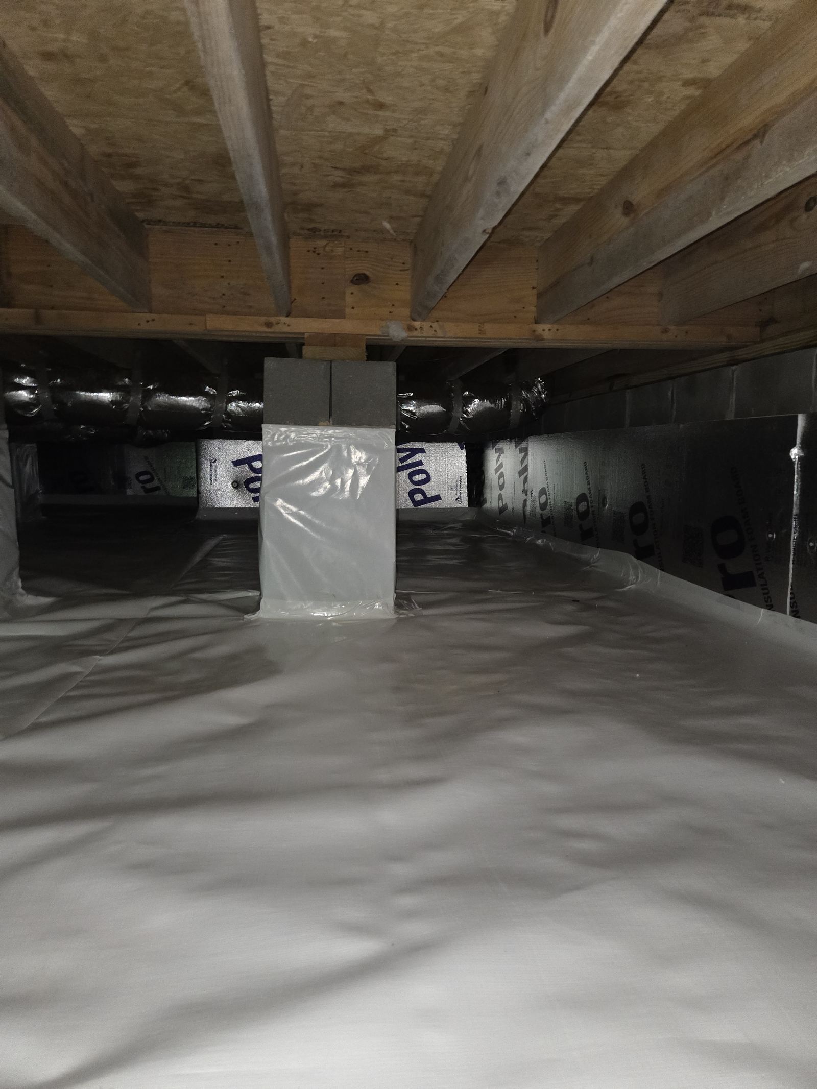 Encapsulated crawlspace with rigid foam insulation board on the foundation walls and a sealed white vapor barrier floor