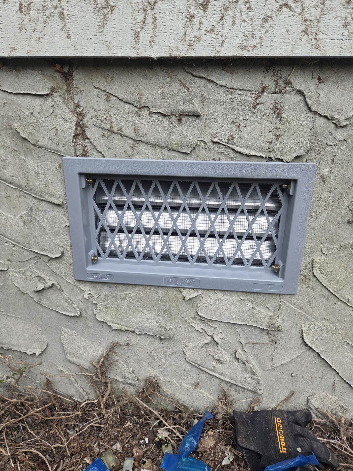 New sealed foundation vent cover installed on the exterior of a home as part of crawlspace encapsulation