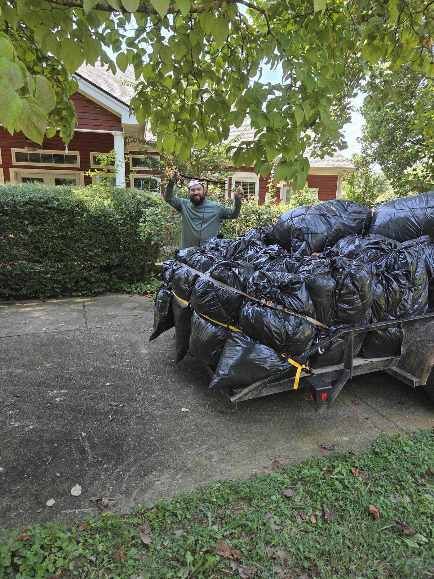 Crawlspace Cowboys owner Zach Franks standing next to a trailer loaded with bagged, moldy insulation removed from a Chattanooga crawlspace
