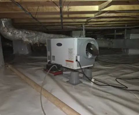Crawlspace dehumidifier set on stands over a white vapor barrier in a newly encapsulated crawlspace