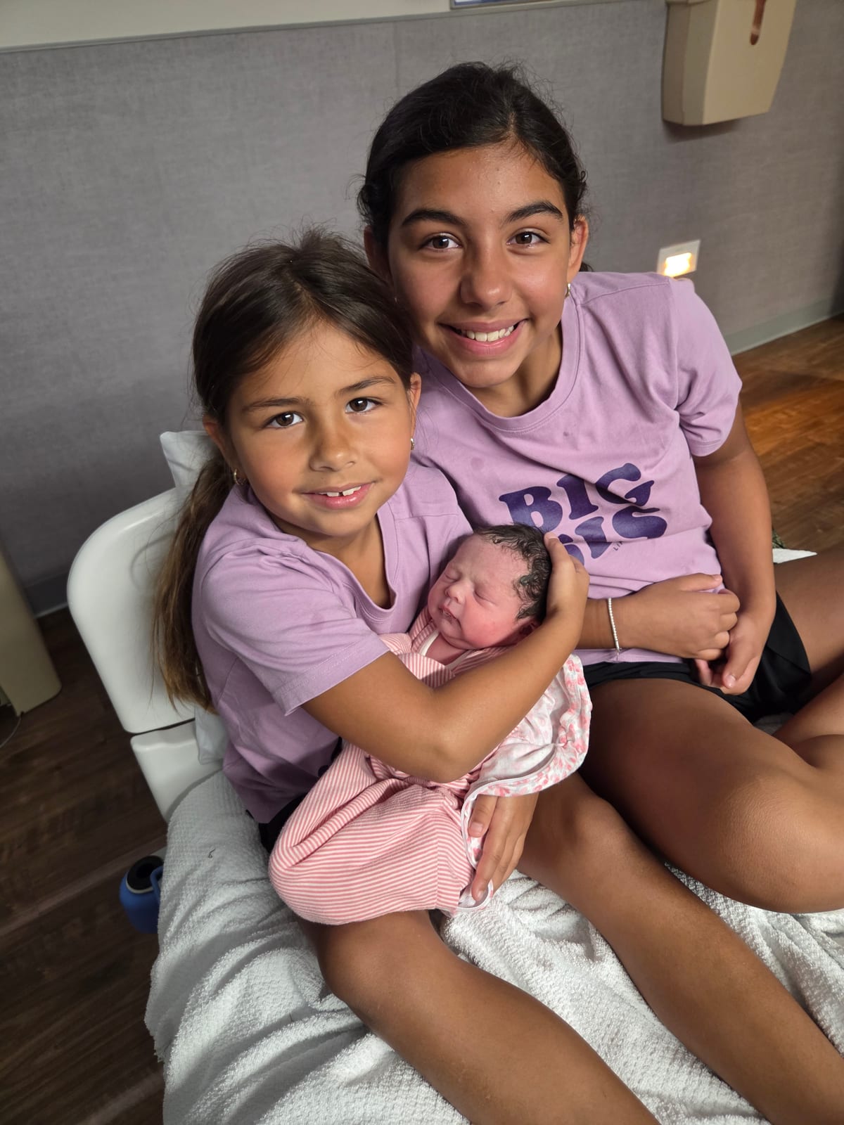 Zach's two older daughters holding their newborn baby sister